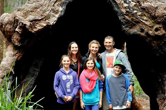 A happy family poses in front of a tree, enjoying their time together while traveling, highlighting the importance of travel insurance
